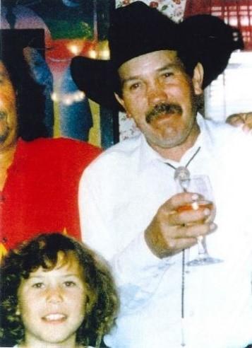 Man wearing cowboy hat smiles at camera with his young daughter at his side