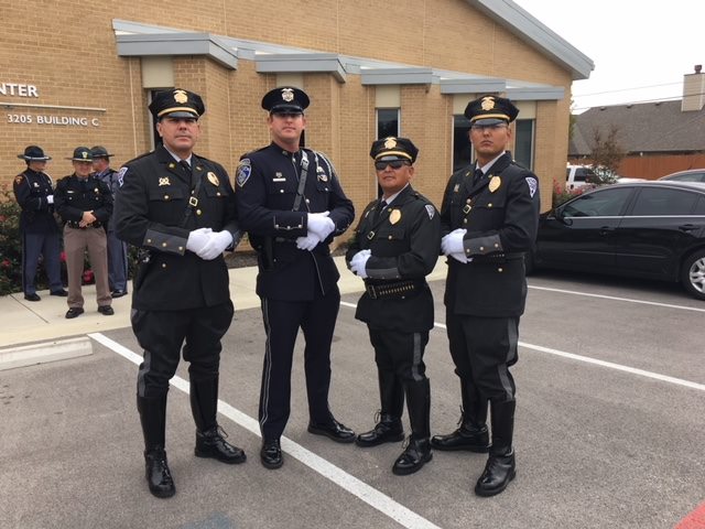 Honor Guard Image 1 Four uniformed officers with hands crossed stand outside yellow brick building