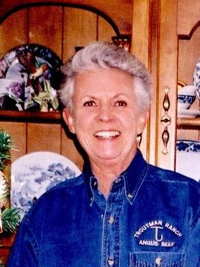 Woman with silver hair wearing blue shirt smiles widely at camera