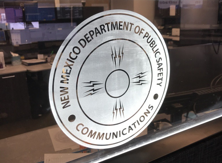 Comms Woman sitting at desk with multiple monitors while someone oversees